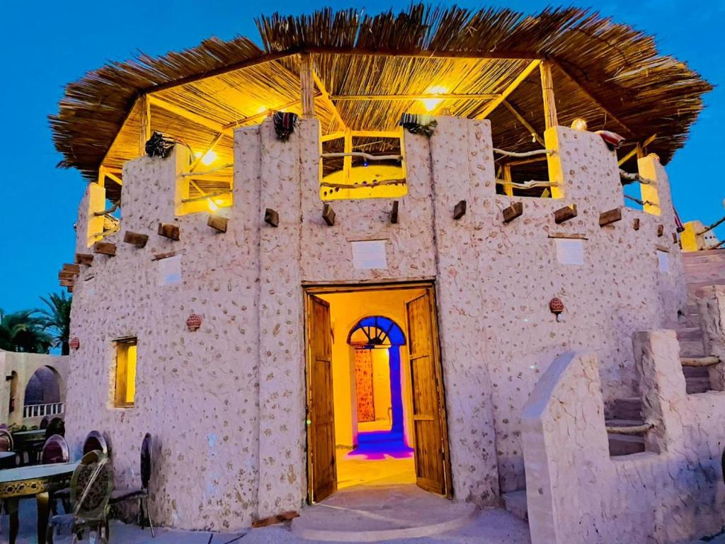 a building in the desert with a blue door at Adrartaziry in Siwa