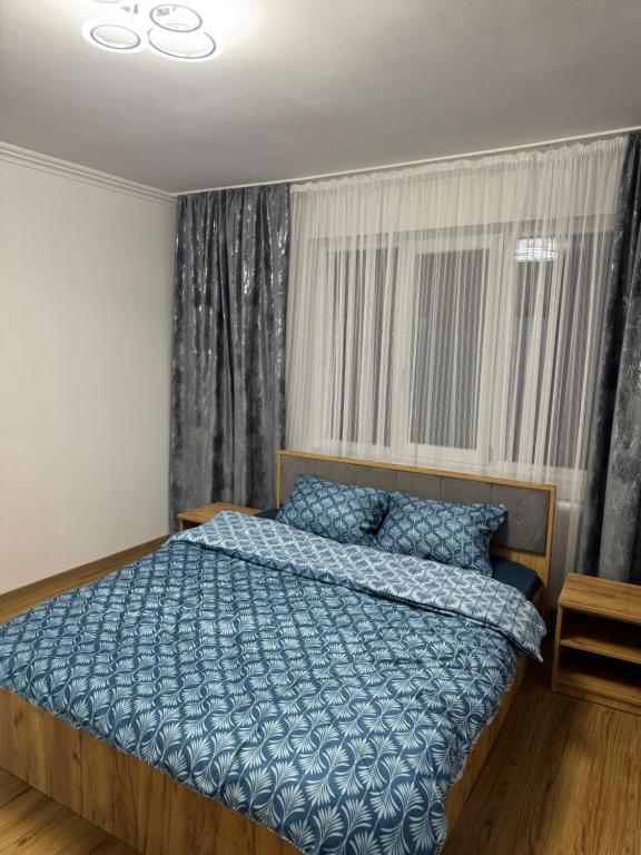 a bedroom with a bed with a blue comforter and a window at Timi&Amos2 in Caransebeş