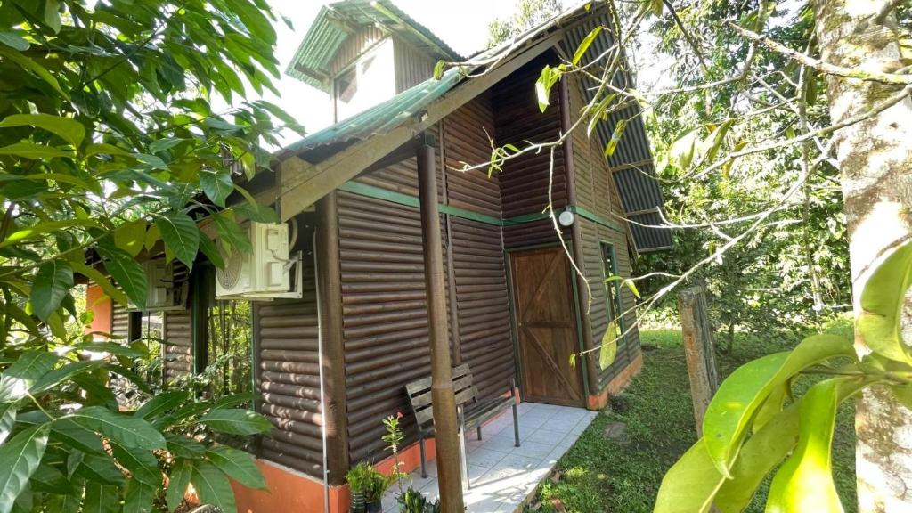 a wooden cabin with a door in a forest at Cabaña Río Sarapiquí in Sarapiquí