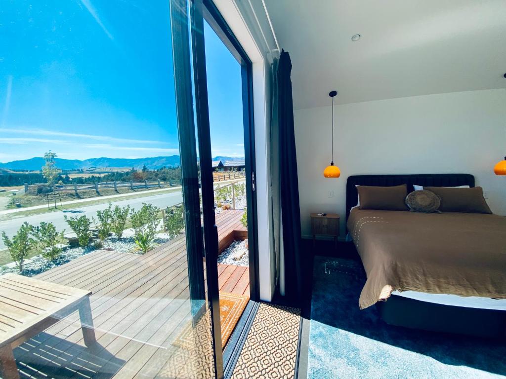 a bedroom with a bed and a balcony with a view at The Modern Alpine Oasis - Mountain Views - Rainfall Shower - Perfect for Couples in Wanaka