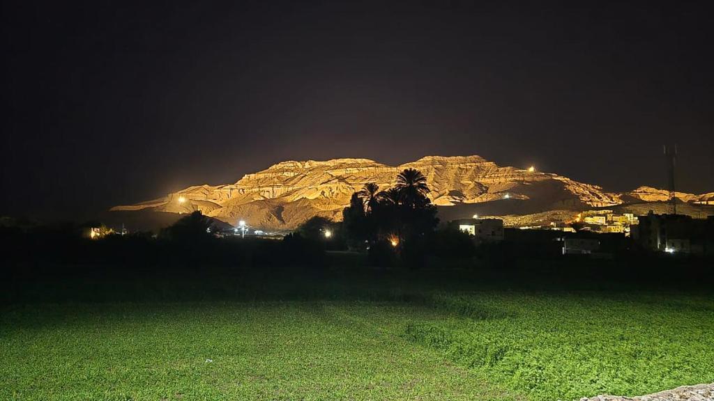 a mountain at night with a green field in front of it at Amenirdis Villa in Al Qurnah
