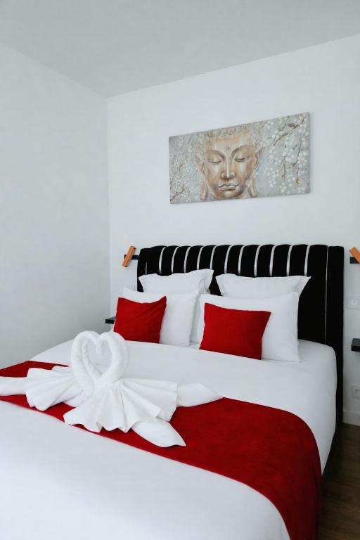 a bed with red and white pillows and a statue at Le Joyau du lac in Charavines