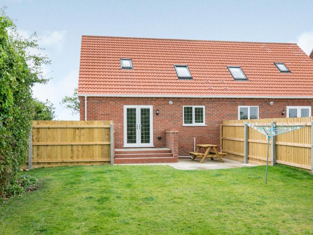 a brick house with a fence and a picnic table at Dawson Park 10 - Uk12669 in Mablethorpe