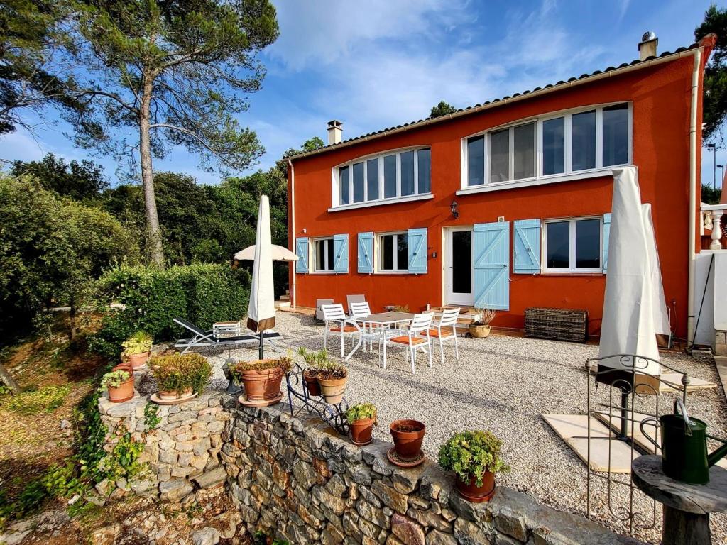 an orange house with a patio with chairs and umbrellas at Gîte Guillaume with swimming pool in Carcès