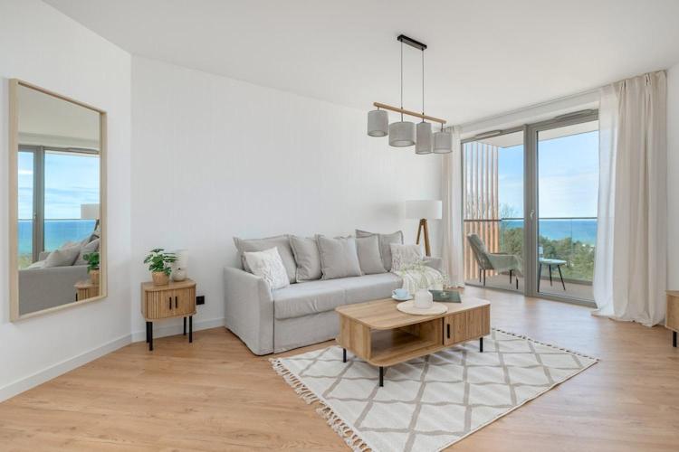 a white living room with a couch and a table at Apartment with direct sea view in Pobierowo