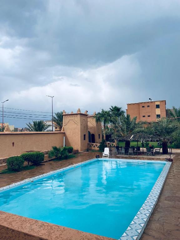 a large blue swimming pool in front of a building at Auberge camping ouadjou in Nkob