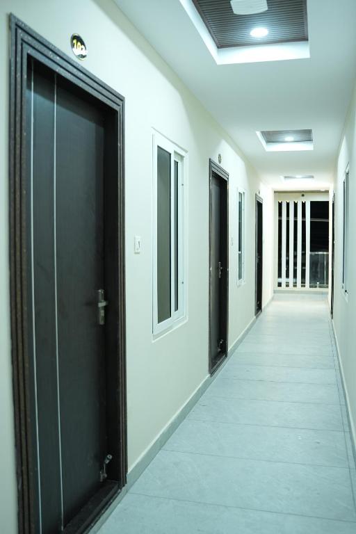a corridor with black doors and white walls at Sri RENUKA VSR Residency in Avanigadda