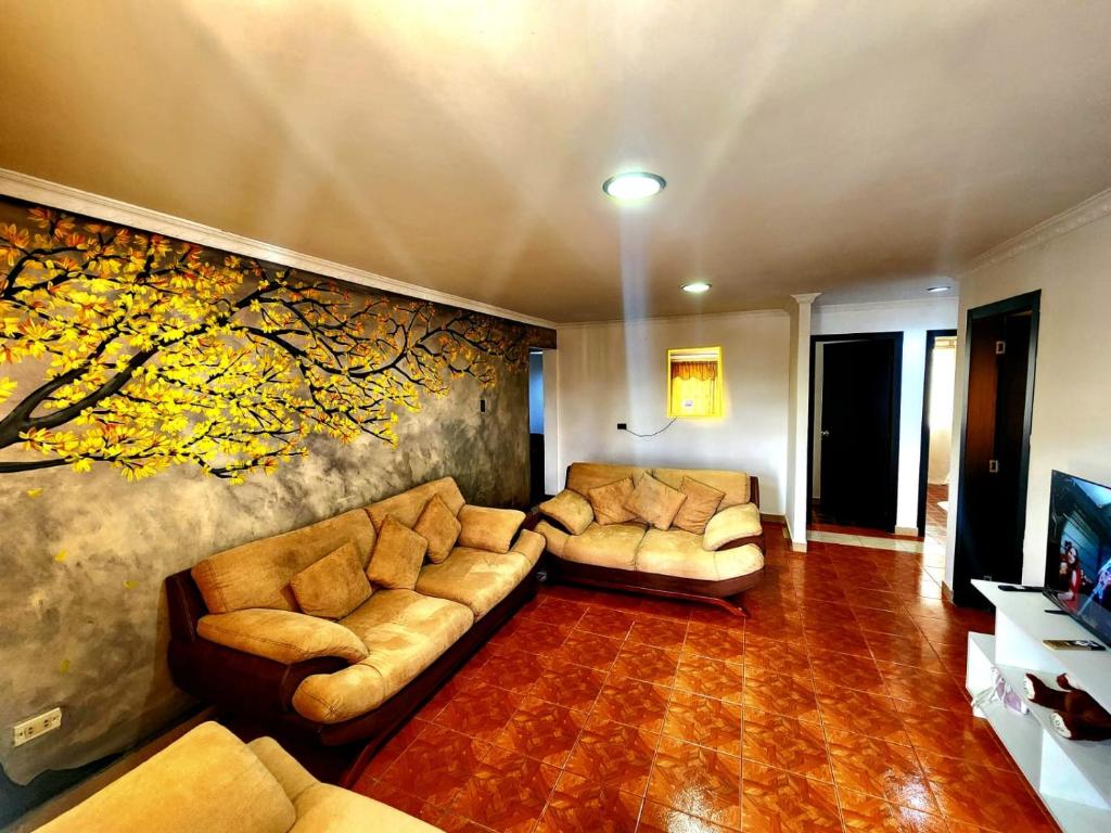 a living room with couches and a painting on the wall at Rincón del Descanso in Loja