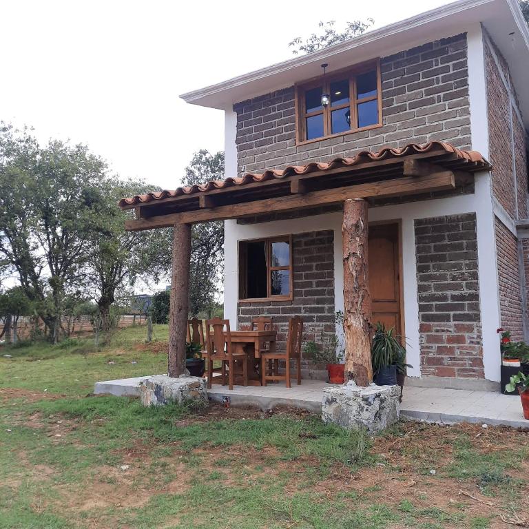 a small brick house with a wooden pergola at Altépetl Cabañas Zacatlán in Tomatlán
