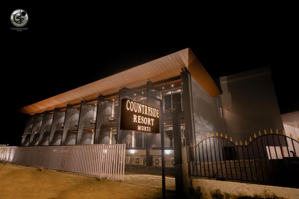 a building with a sign in front of it at night at COUNTRYSIDE RESORT MURTi in Chālsa Mahābāri