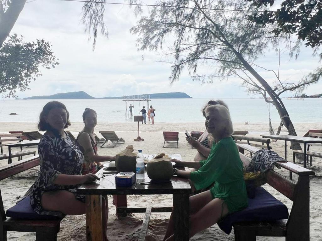 tre donne sedute a un tavolo da picnic sulla spiaggia di Rock Sand Hostel a Phumĭ Kâoh Rŏng