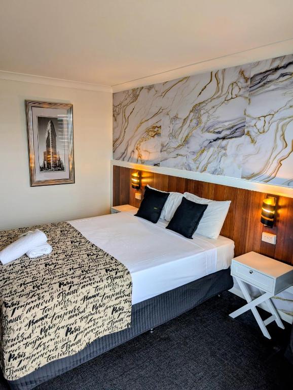 a hotel room with a large bed and a marble wall at Hampton Villa Motel in Rockhampton
