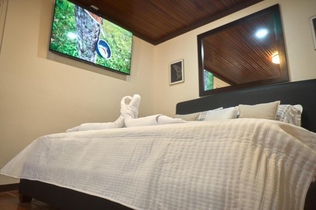 a bedroom with a white bed with a tv on the wall at Airport SJO Inn in Santiago Este