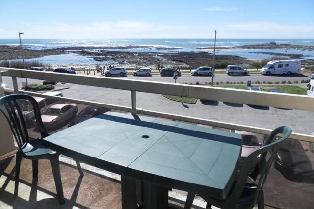 a table and chairs on a balcony with a view of a parking lot at Apt 4 pers - Magnifique vue mer - Terrasse - 50 m de la plage - Bleuenn in Le Fort-Bloqué