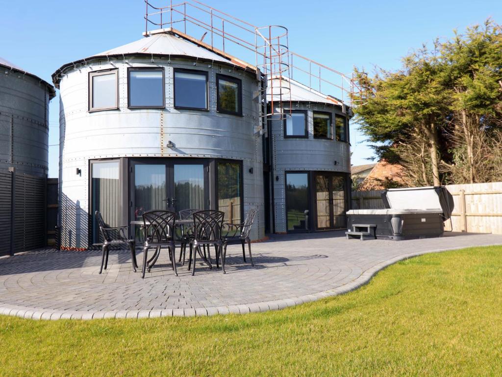 a circular patio with a table and chairs in front of a house at The Barley Silo in Ipswich