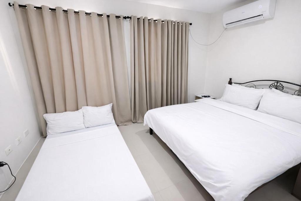 zwei Betten in einem Zimmer mit weißen Wänden und Vorhängen in der Unterkunft Ben & Ben in San Fernando