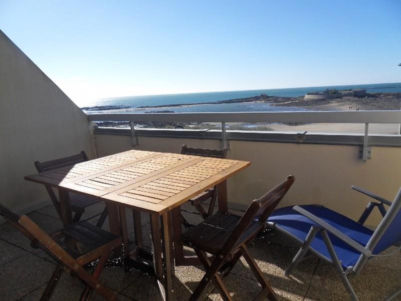 uma mesa e cadeiras numa varanda com vista para o oceano em Apt 4 à 5 personnes magnifique vue mer, terrasse - 50 m de la plage -MELWENN em Le Fort-Bloqué