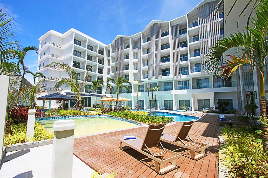 a large apartment building with a swimming pool and chairs at Luxu Hotel and Resort in Panglao Island
