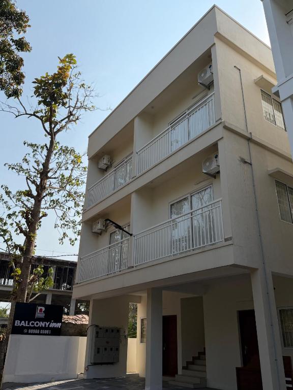 a building with a balcony and a tree at Balcony inn in Nedumbassery