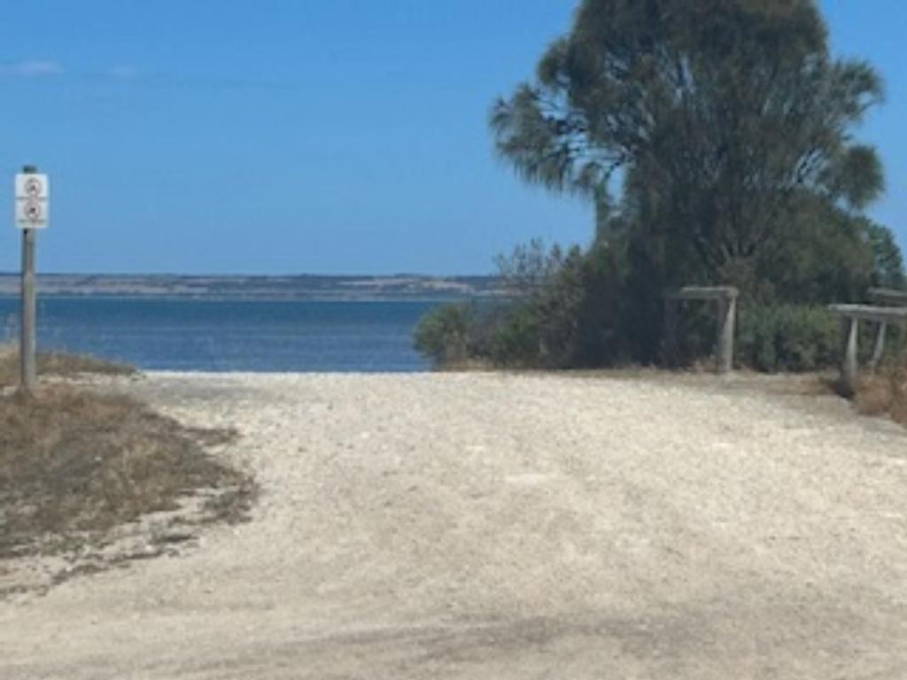 a dirt road next to a body of water at KI Caravan Park, Kingscote in Kingscote
