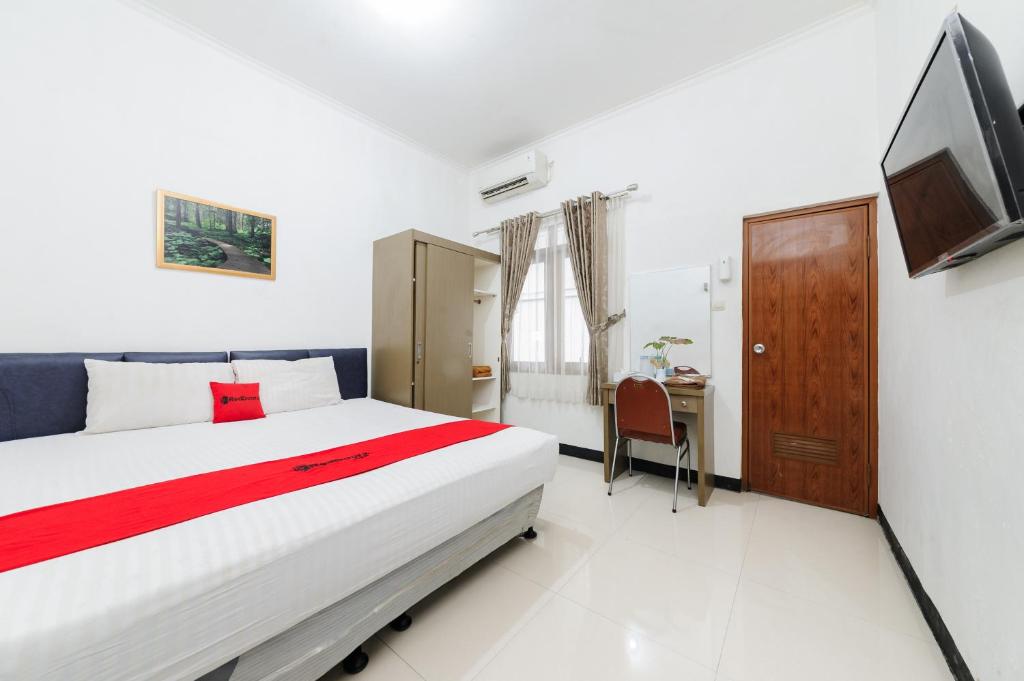 a bedroom with a bed and a tv and a desk at RedDoorz at Batutulis Bogor by House of M in Bogor
