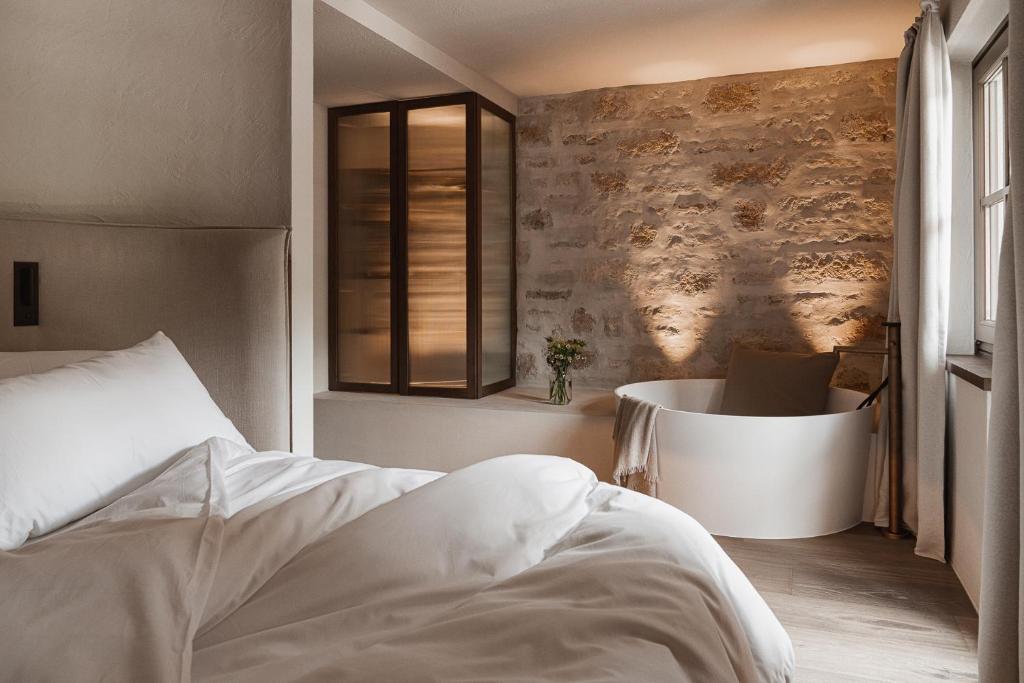 a bedroom with a bed and a tub in it at stieg'nhaus Design Boutique Hotel in Mühlbach am Hochkönig