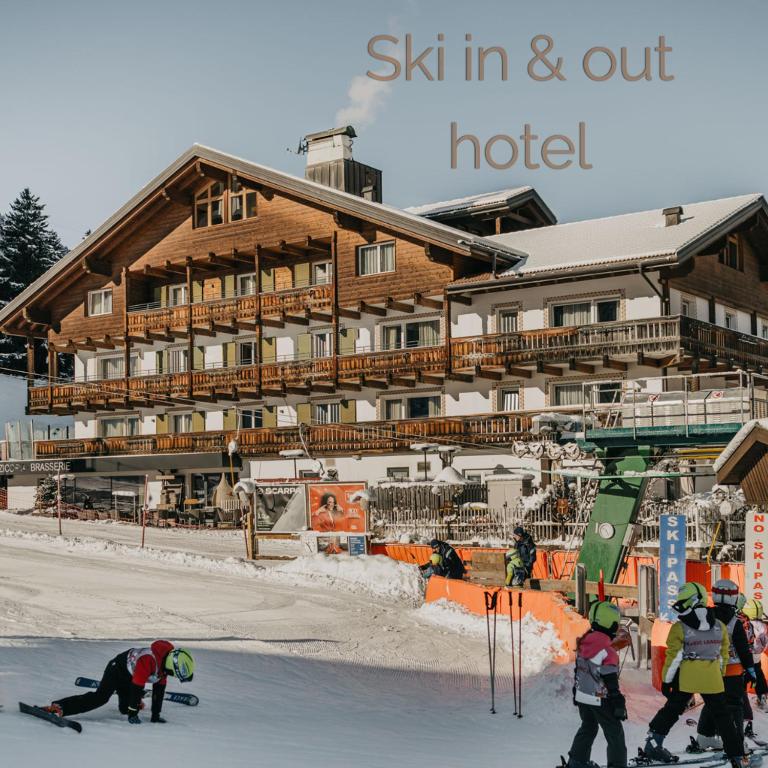 a group of people skiing in front of a hotel at Hotel Hell in Ortisei