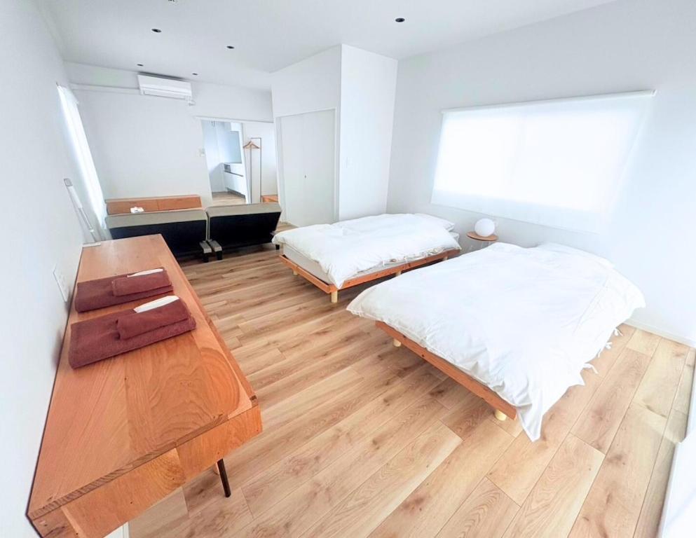 a bedroom with two beds and a wooden table at 果実の見える宿 in Koshu