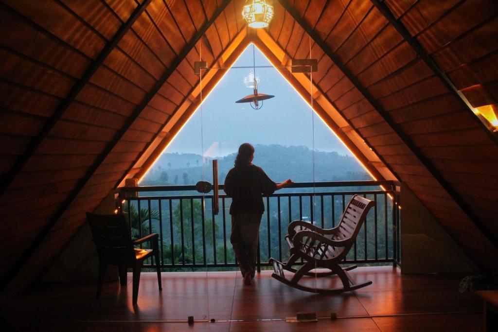 a man standing in a tent looking out of a window at Mountain View A frame Pool Villa in Meppādi