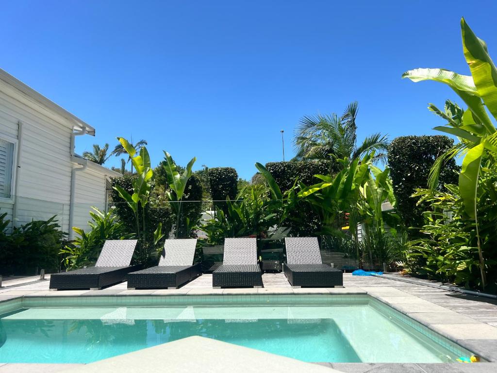 a swimming pool with lounge chairs next to a house at Bamboo Beach House & Studio in Byron Bay