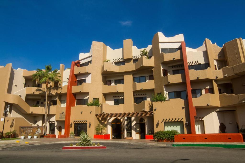 a large building with palm trees in front of it at Marina Cabo Plaza Town & Beach Condos in Cabo San Lucas