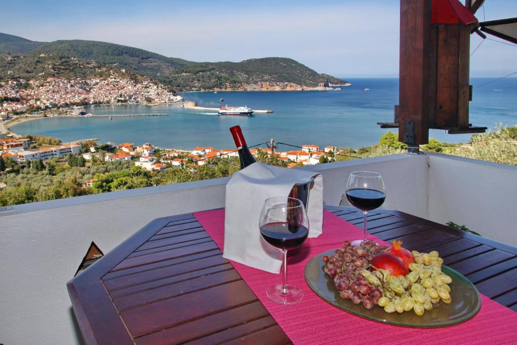 uma mesa com um prato de comida e copos de vinho em Irene' s Paradise em Skopelos Town