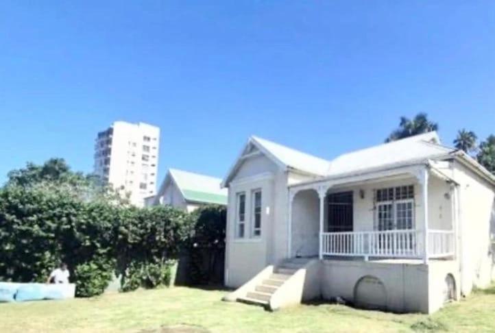 a small white house with stairs in a yard at Halford Backpackers, Durban in Durban