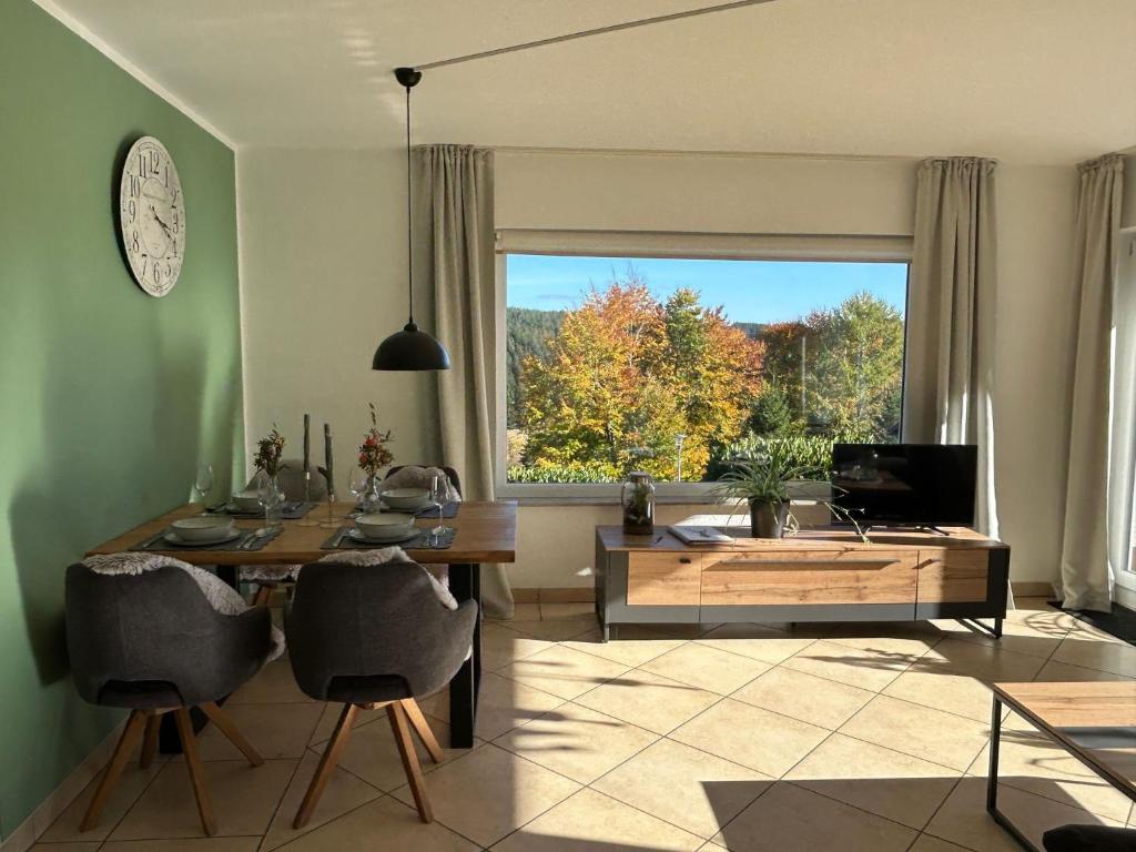 a living room with a table and a large window at Tannenblick in Schönwald