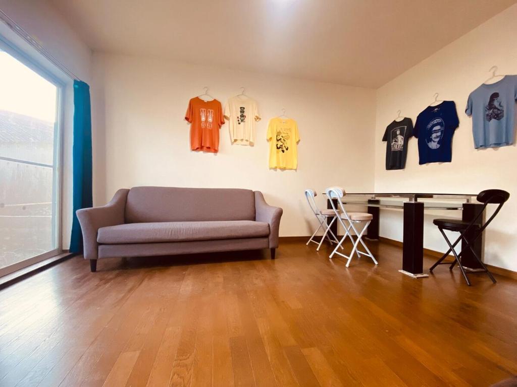 ein Wohnzimmer mit einer Couch und Hemden an der Wand in der Unterkunft Guest House 楽風 in Anan