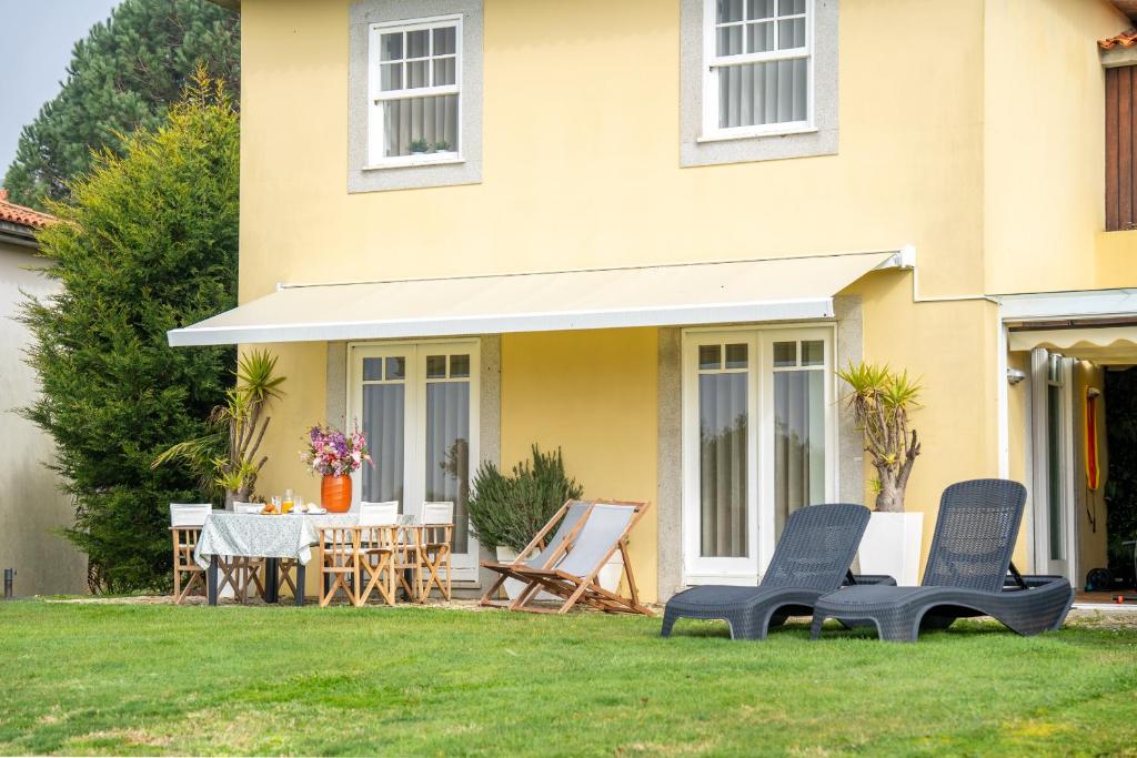 a house with two chairs and a table in the yard at Refúgio das Velhas in Vila Nova de Cerveira