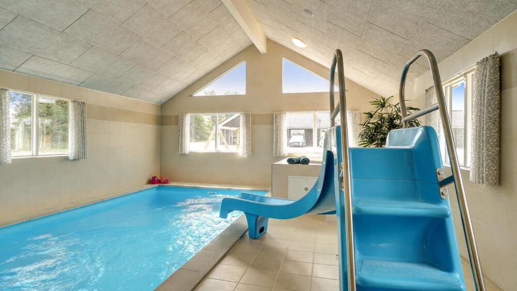 a large swimming pool with a blue slide in a room at Villavilla 451 - Grenå Strand, Østjylland in Grenå