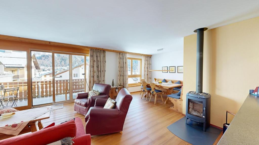a living room with a fireplace and a couch and a stove at Apartment Macun in Silvaplana