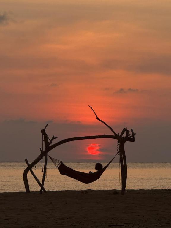a man in a hammock on the beach at sunset at Marinthara in Ko Phra Thong