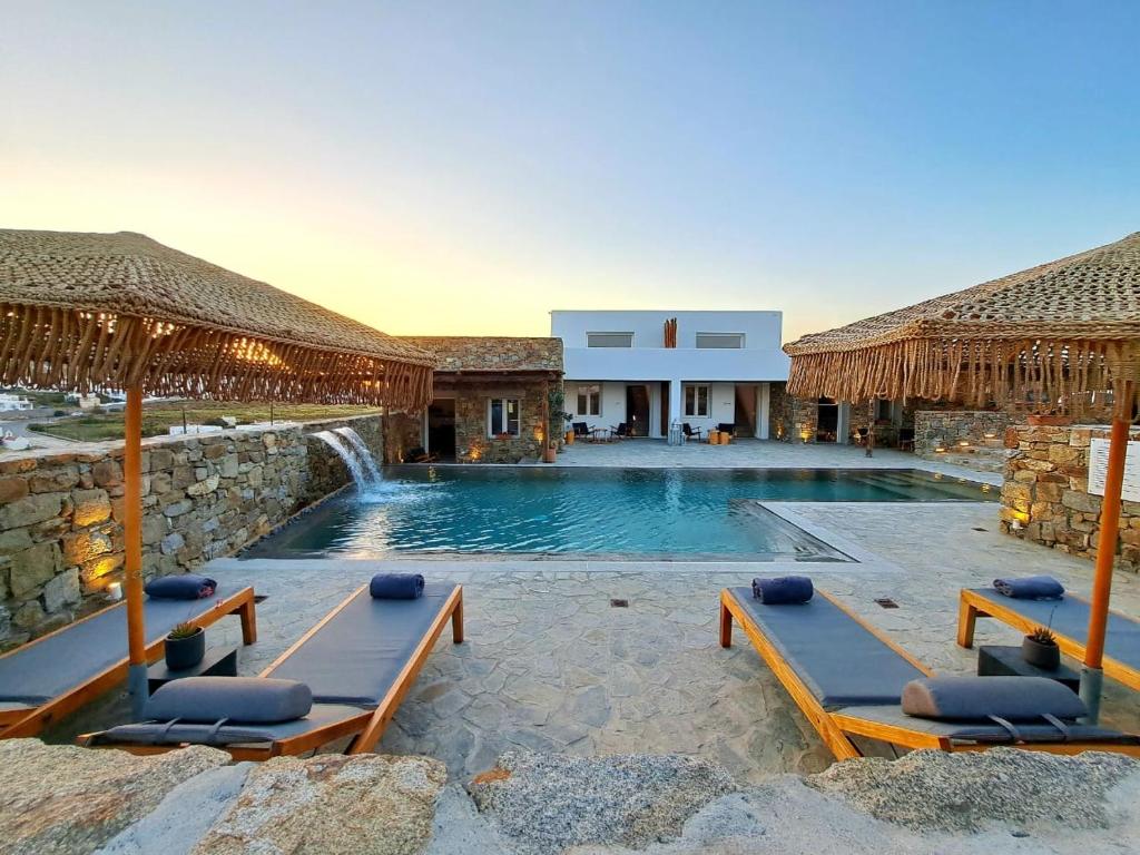 a swimming pool with two lounge chairs and a resort at Mykonos Dot Art Homes in Ano Mera