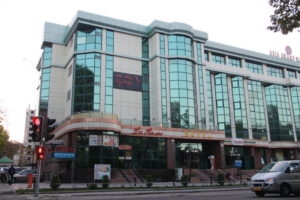 a large building with glass windows on a city street at Taj Palace Hotel & Spa in Dushanbe