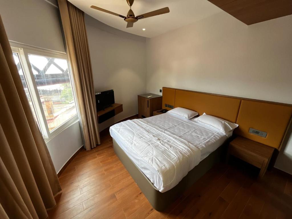 a bedroom with a bed and a large window at Cloud Nine Hotel - Kuthuparamba in Kūttuparamba