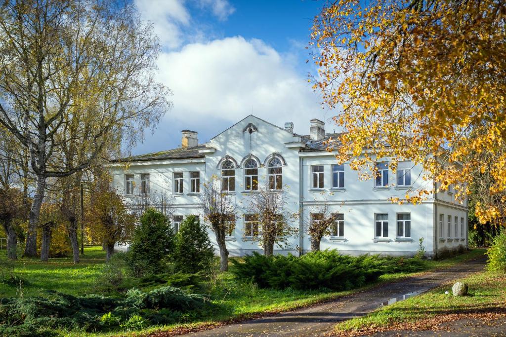 a white house with trees in front of it at Bērzgala Viesu Nams in Stradi