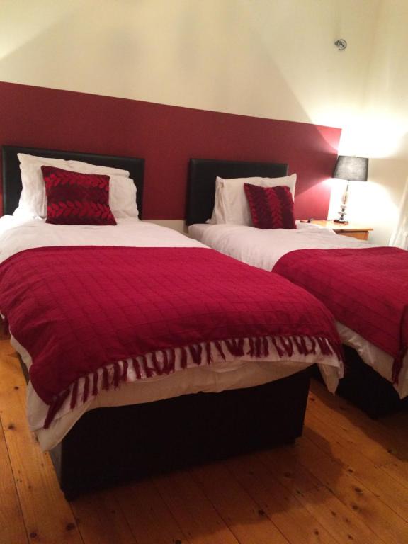 two beds in a room with red walls at B&B on Ballyneety Golf Course in Limerick