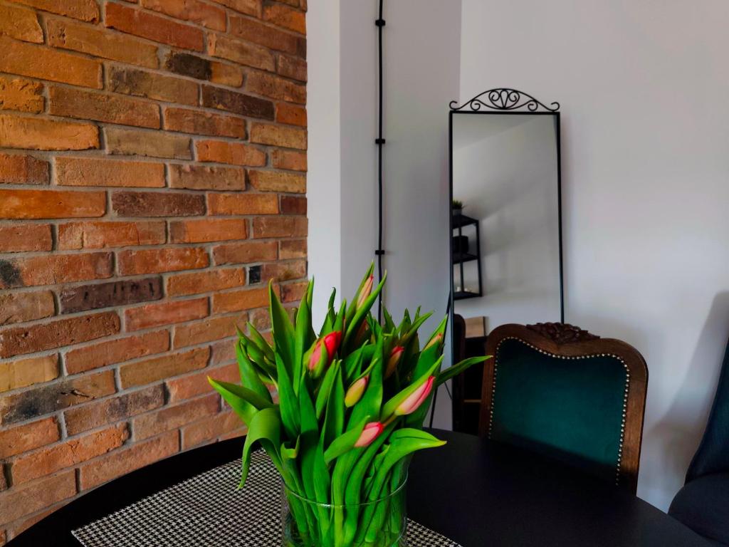 a table with a vase of flowers and a mirror at LOFT Jana z Kolna in Koszalin