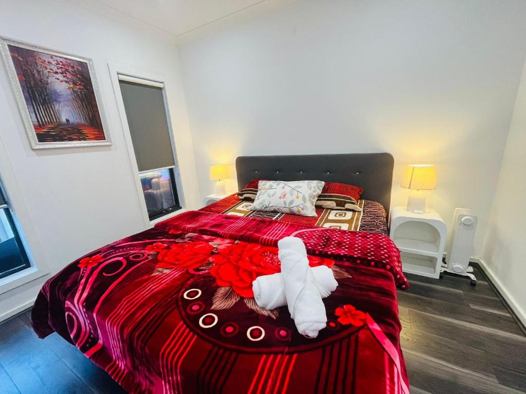 a bedroom with a large bed with a red blanket at My Home II in Tarneit