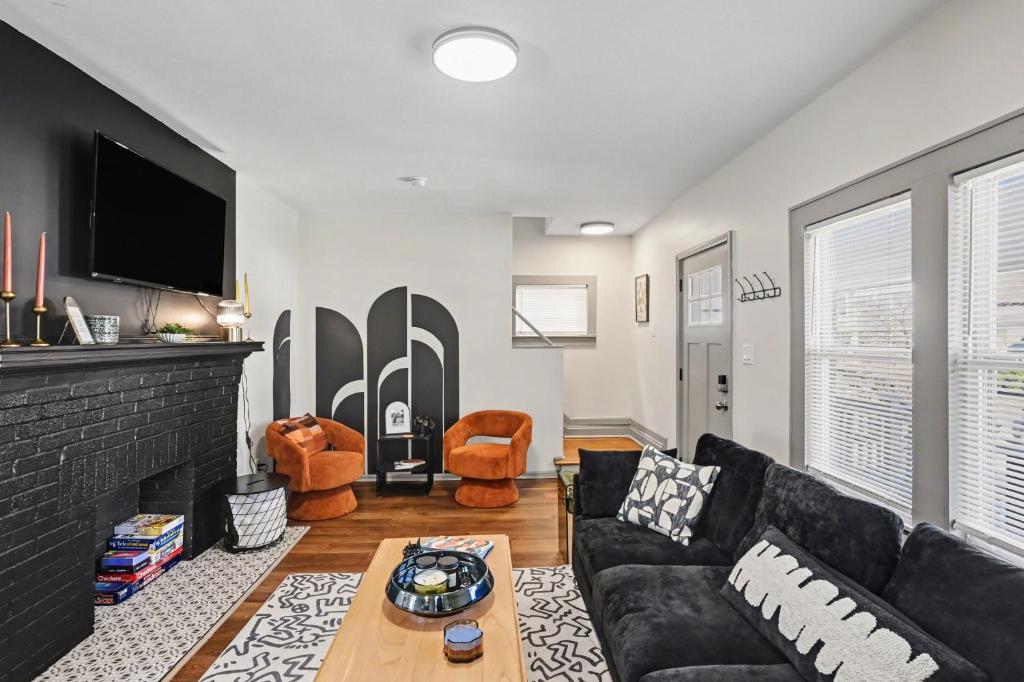 a living room with a black couch and a fireplace at Cozy 2BR Near Ohio State - Private Yard - Parking in Columbus