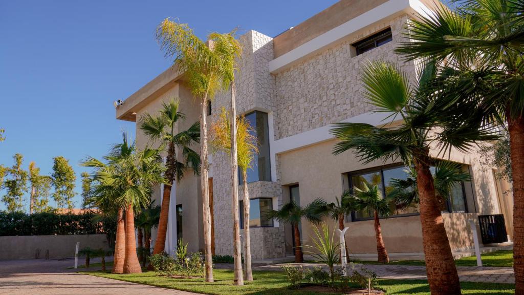 a building with palm trees in front of it at Villa Kaima Marrakech jacuzzi chauffé in Marrakesh