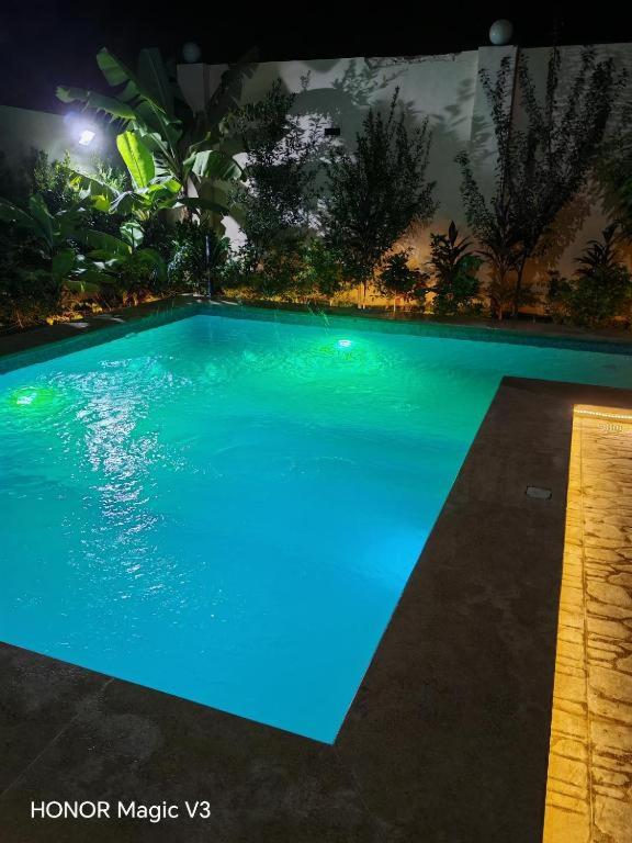 a large blue swimming pool at night at Loay Villa Stella Helipolis in Madīnat aţ Ţalāʼi‘