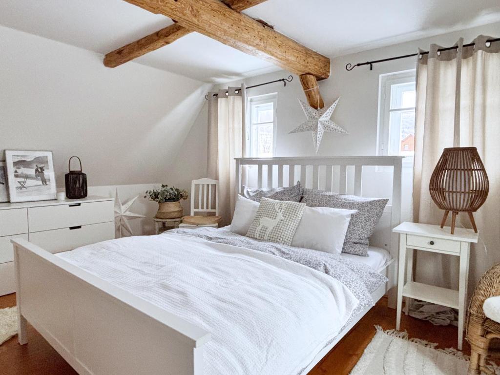 a white bedroom with a white bed and a wooden ceiling at Venkovský Útulek in Lázně Libverda